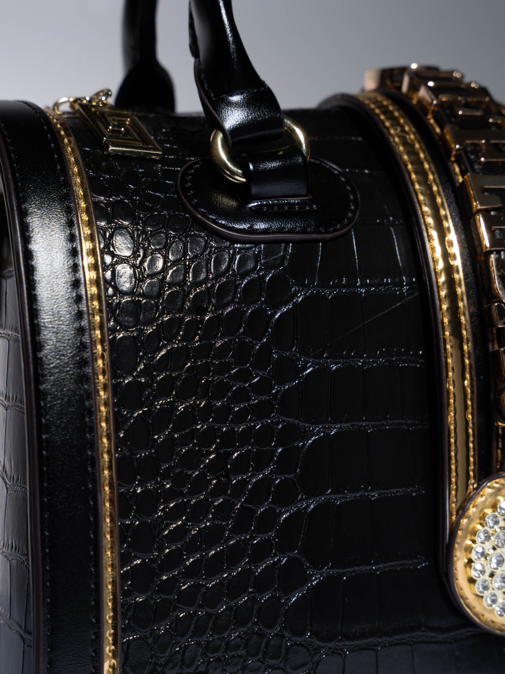Black handbag with gold accents on a gray background