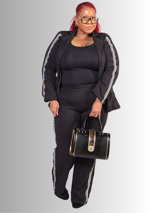 Woman wearing a #Black | Pinstripe tracksuit holding a handbag on a gray background