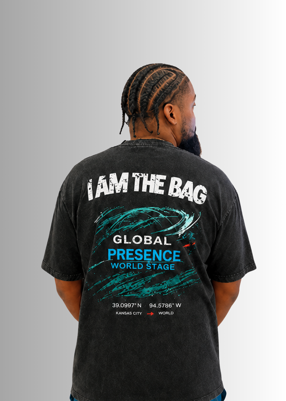 Man wearing a Duffle Bag black t-shirt with I AM THE BAG, sitting against a gray background