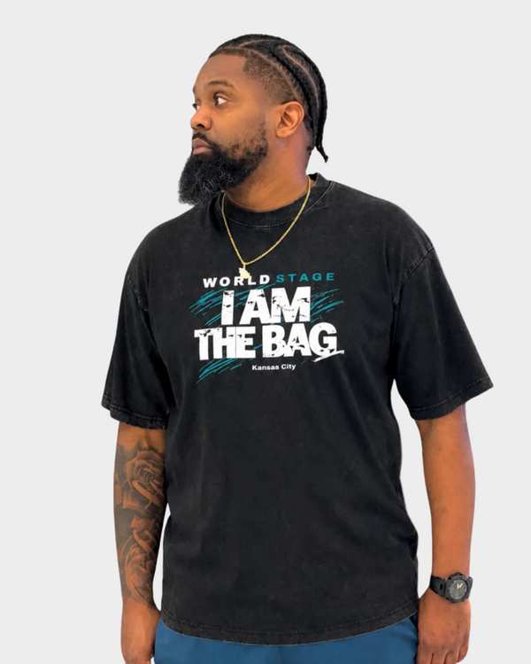 Man wearing a Duffle Bag black t-shirt with I AM THE BAG on a gray background