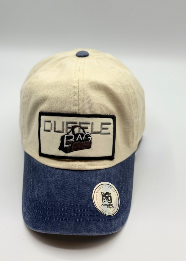 Cream and denim distressed dad hat with Duffle Bag logo, featuring a cream crown and distressed denim brim.