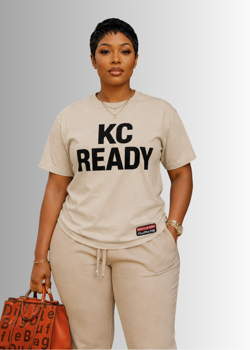 Person wearing a beige Duffle Bag 'KC READY' t-shirt with a plain background