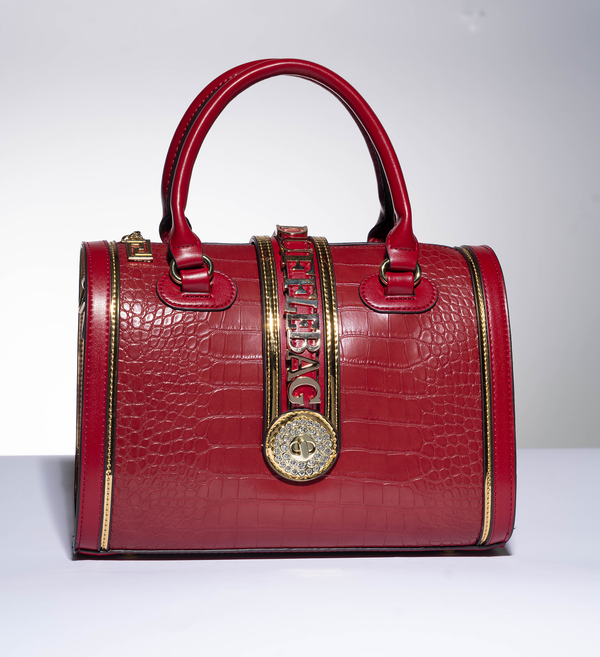 #Red handbag with gold accents and a visible dufflebag logo on a white background